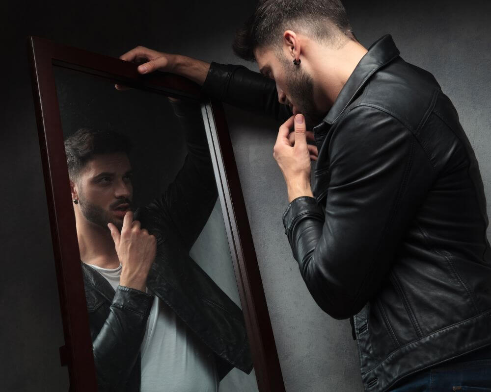 a narcissist man looking at a mirror obsessively