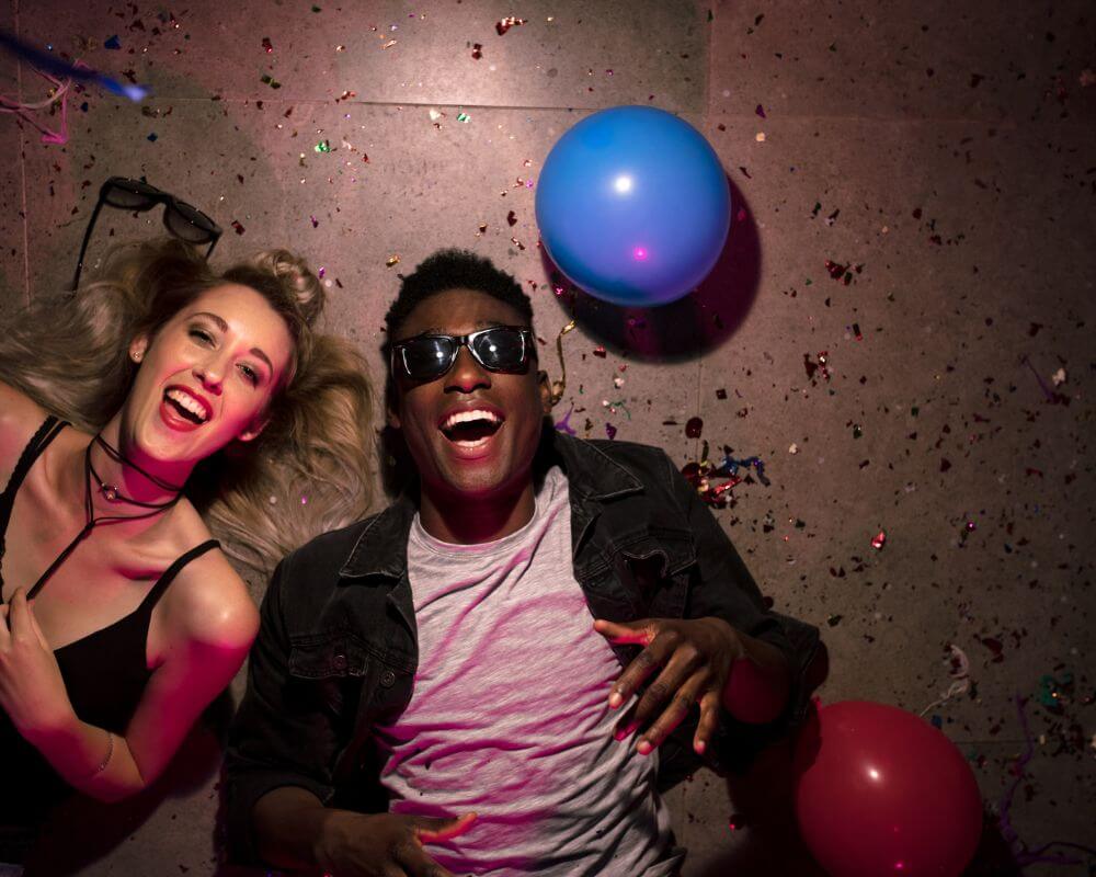 a couple lying on the floor in a party happily and smiling 