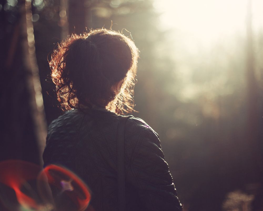 an alone woman looking at sunlight and trees