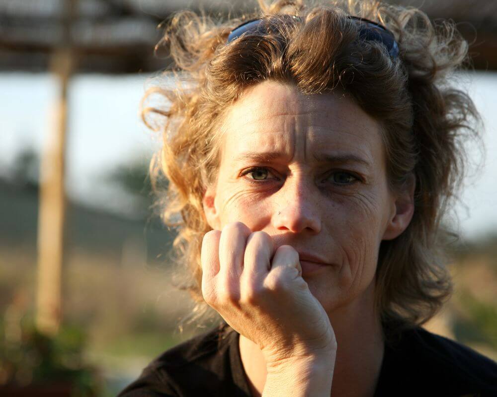 an isolated woman staring straight ahead , her hands lent on her face