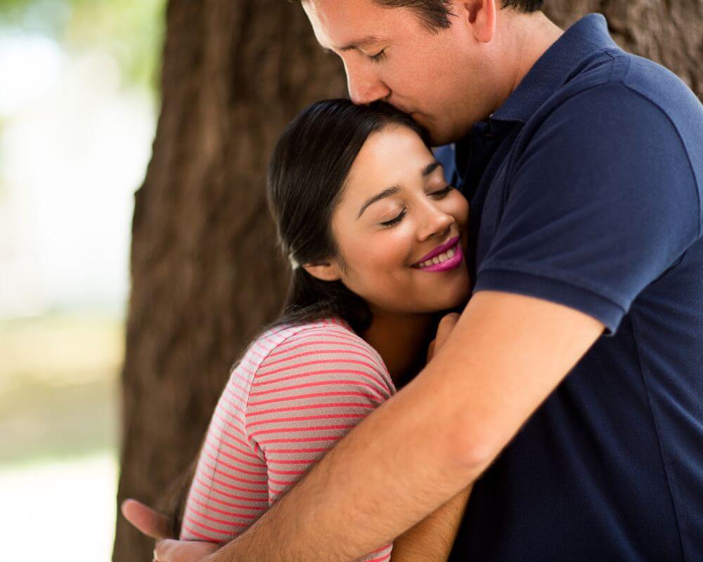 a man kissing a woman affectionately on the forehead