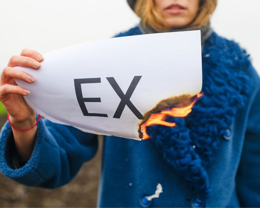 woman burning a paper with "EX" written 